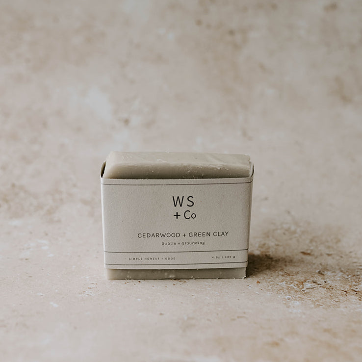 A packaged bar of Cedarwood + Green Clay soap with the brand WS + Co visible on the label, placed on a textured background.