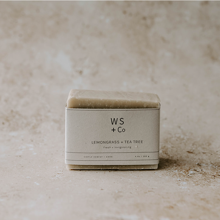A packaged bar of lemongrass and tea tree soap with the brand WS + Co visible on the label, placed on a textured background.