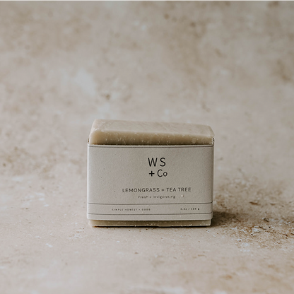 A packaged bar of lemongrass and tea tree soap with the brand WS + Co visible on the label, placed on a textured background.