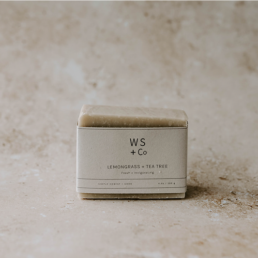 A packaged bar of lemongrass and tea tree soap with the brand WS + Co visible on the label, placed on a textured background.