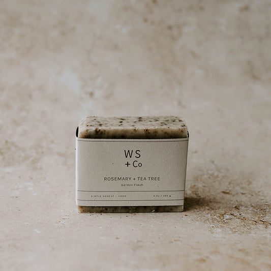 A bar of Rosemary + Tea Tree soap with exfoliants, packaged in a simple white box with the brand WS + Co visible.