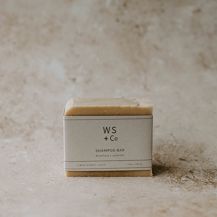 A shampoo soap bar with packaging labeled 'WS + Co SHAMPOO BAR' on a textured background.