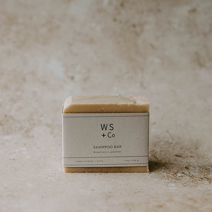 A shampoo soap bar with packaging labeled 'WS + Co SHAMPOO BAR' on a textured background.