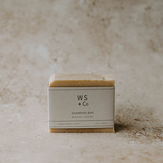 A shampoo soap bar with packaging labeled 'WS + Co SHAMPOO BAR' on a textured background.